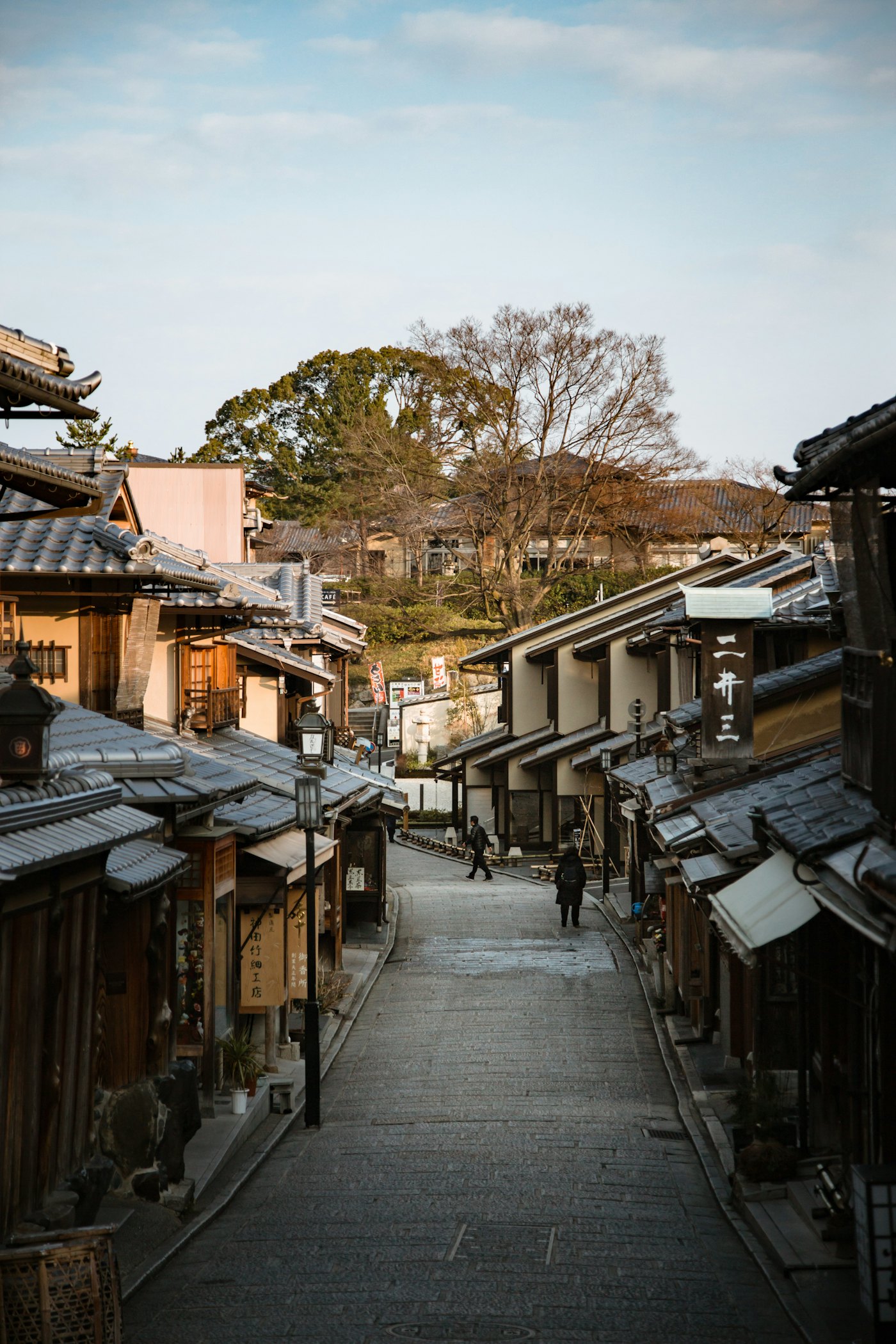 Traditional wooden houses and tiled roofs on a sloping street in Kyoto